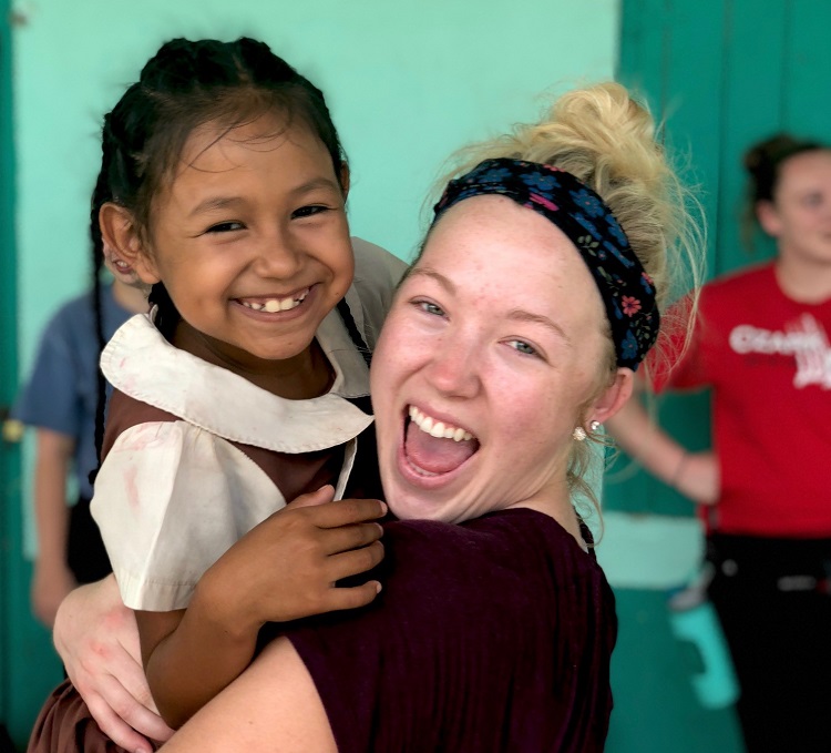Volleyball player Danielle Curnes holding a little girl from Belize and smiling