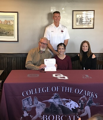 Bianca Cunningham seated at table with parents and Coach Larsen in background