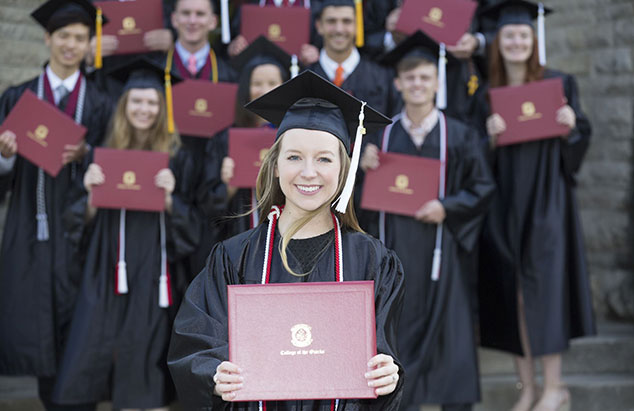 Students in gruation regalia holding diploma covers
