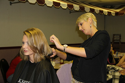 Take One owner Lindsay Eskew cutting C of O student Hannah James' hair